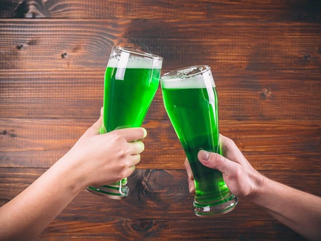 St Patrick's Day concept two mug on hands green beer against wooden background