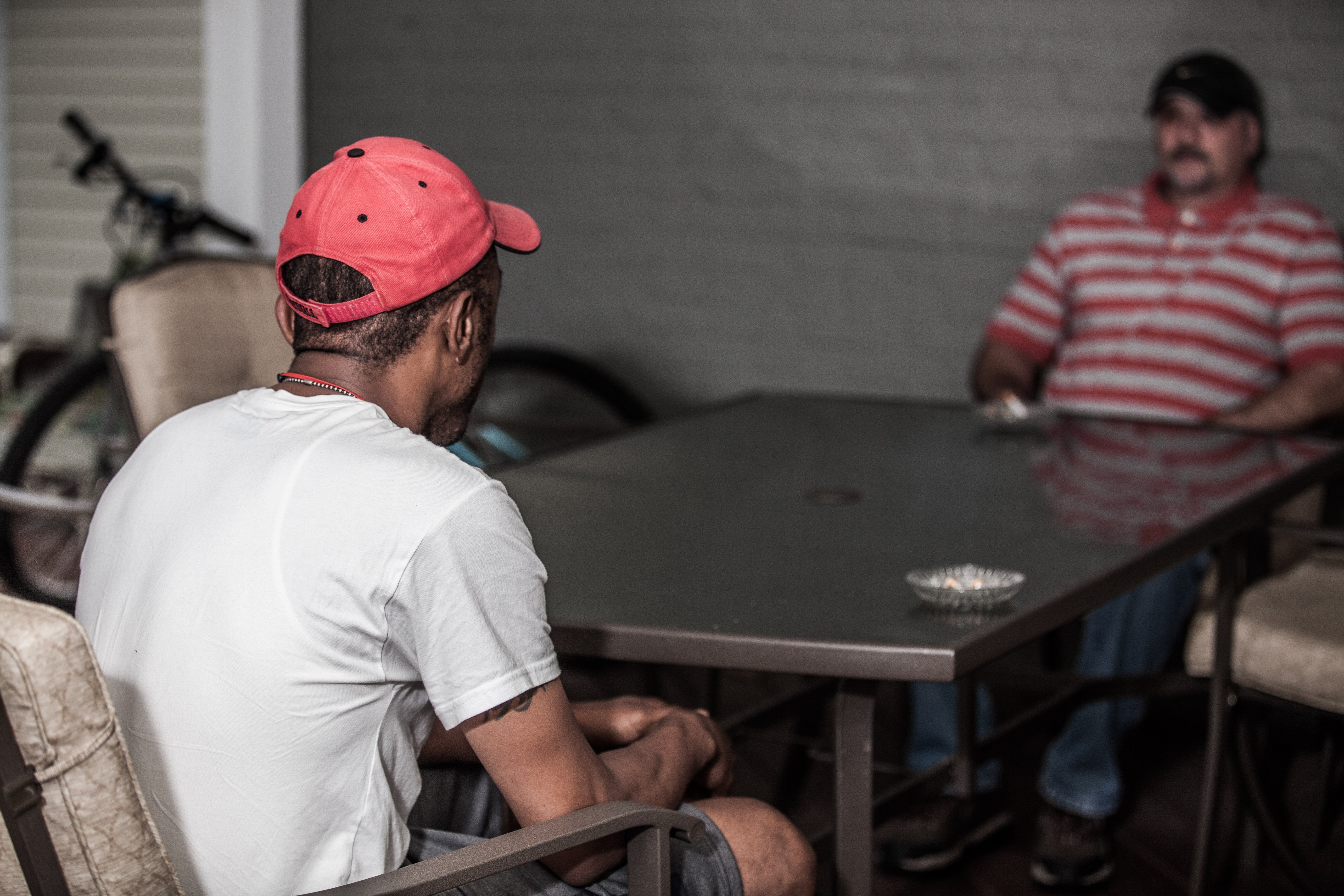 Two residents at The Glade House chat on the back porch of The Glade House. (Facing gentleman gave permission for his face to be photographed).