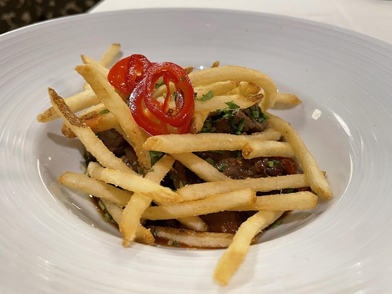 A steak with a Peruvian accent, lomo saltado at the old Anoosh Bistro was a beefy appetizer (topped with crisp fries and zippy red peppers) big enough to serve as a main dish. - Robin Garr