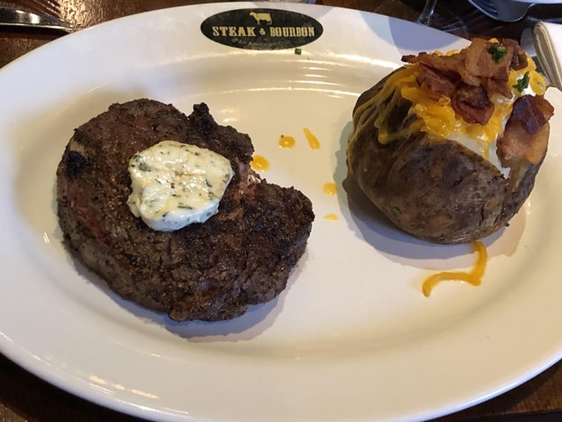 The 14-ounce Certified Angus rib eye steak and loaded baked potato at Steak & Bourbon was $38 for our 2019 visit, and was plenty big enough to share. - Robin Garr